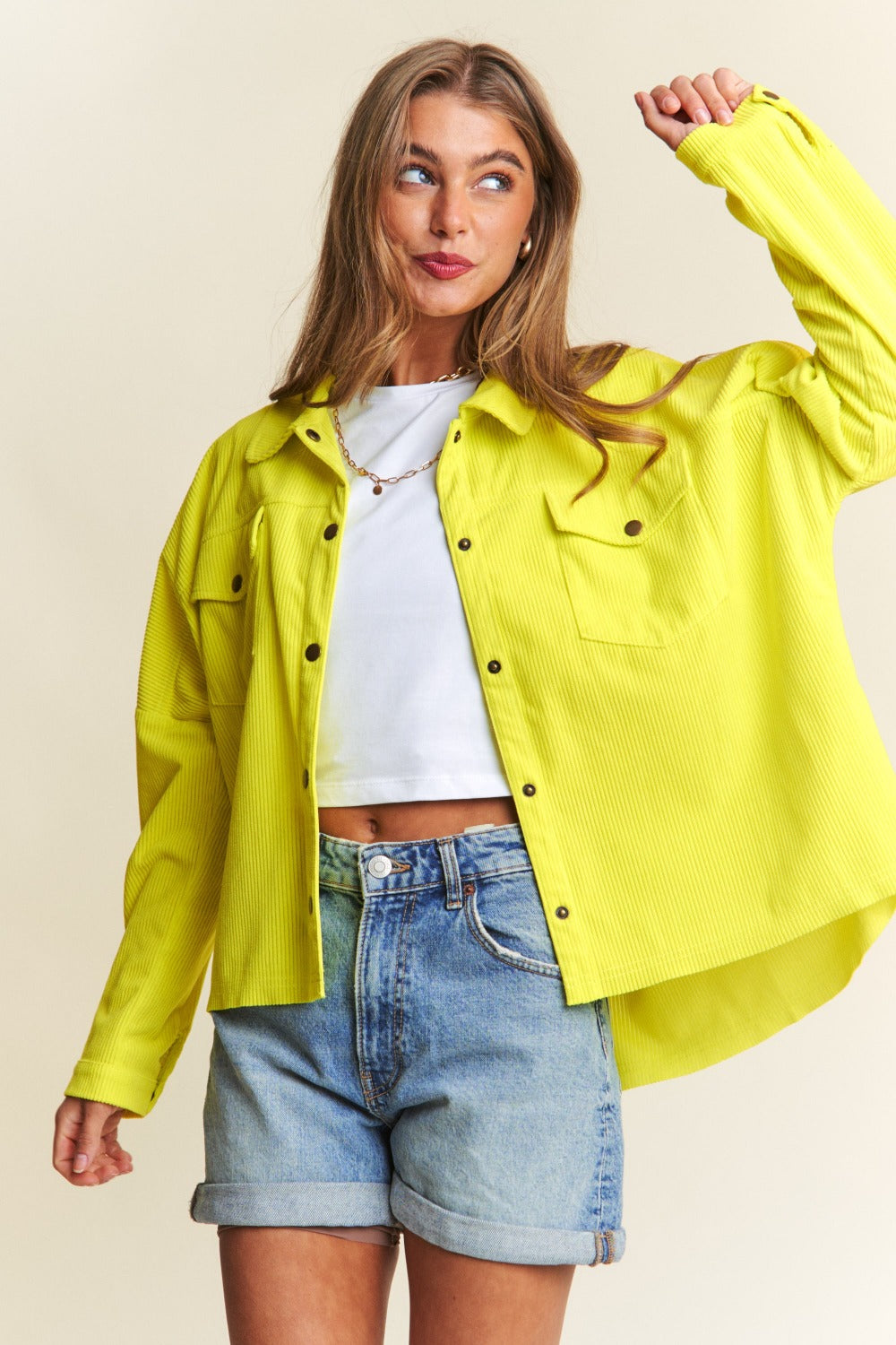 Stylish woman wearing a yellow snap down long sleeve high low shacket and denim shorts, showcasing a trendy and versatile look.