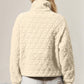 Woman wearing cream quilted sweatshirt with half zip and pocket, showcasing cozy and stylish design against a neutral background.