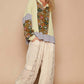 Model wearing a stylish patchwork top with pastel colors and oversized pants, showcasing a trendy bohemian look.