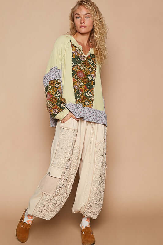 Model wearing a stylish patchwork top with pastel colors and oversized pants, showcasing a trendy bohemian look.