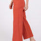 Woman wearing wide-leg cropped pants in rust color with front and back pockets, showcasing a comfortable and stylish design with sandals.