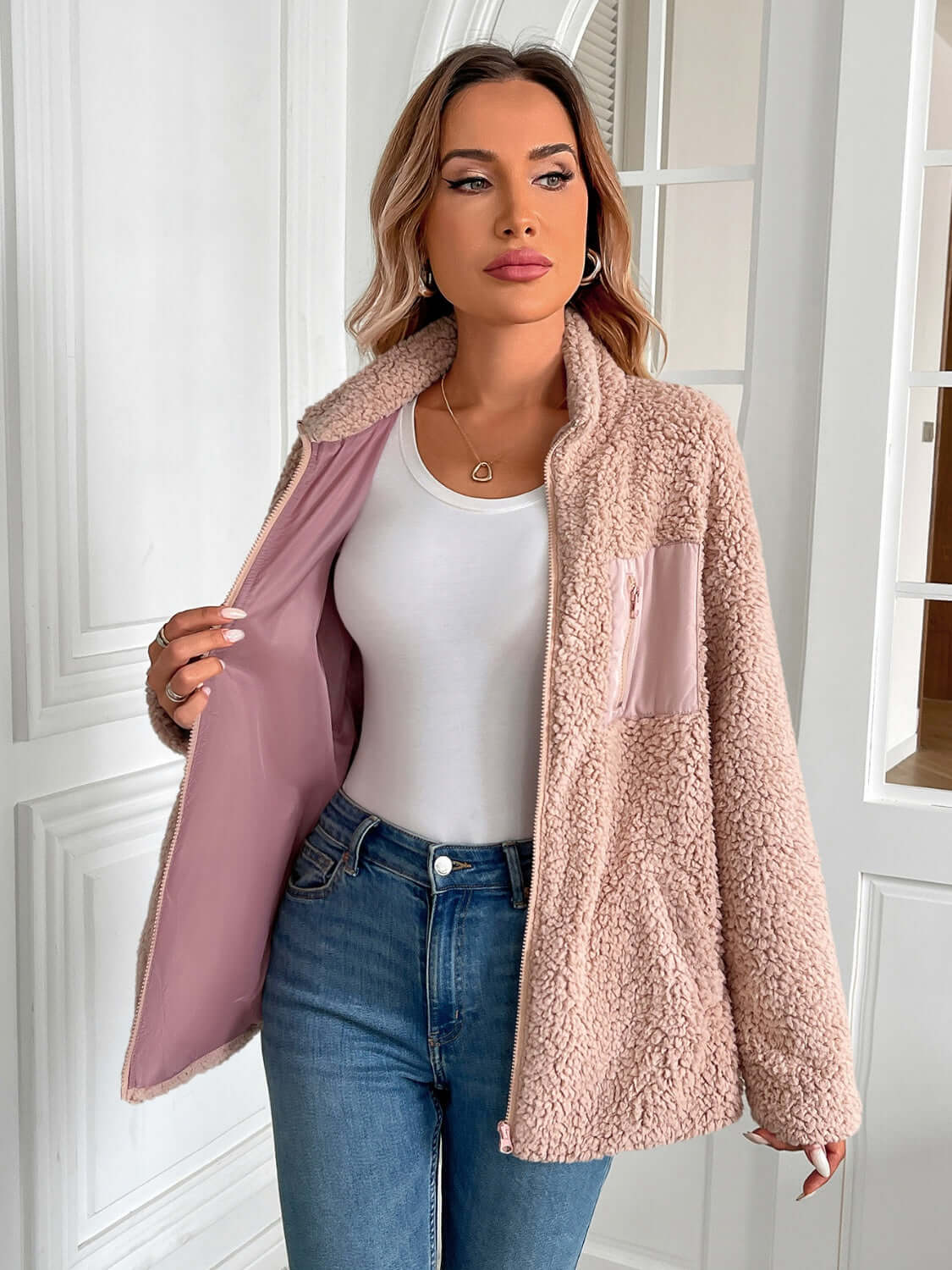 Woman wearing Ivy Lane Zip Up Long Sleeve Fuzzy Jacket in pink, paired with white top and jeans, showcasing cozy style.