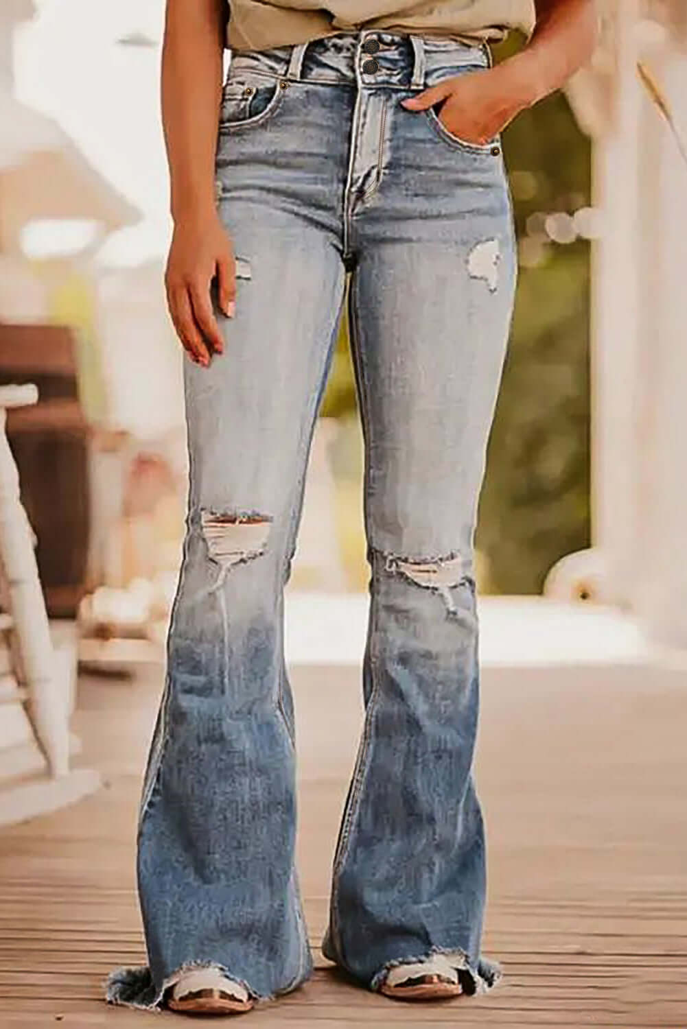 Woman wearing stylish distressed raw hem bootcut jeans with slight stretch, perfect for a casual chic look, featuring ripped details and high rise fit.