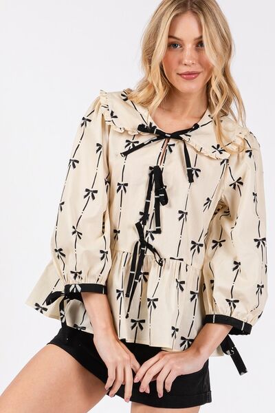 SAGE + FIG Bow Print Tie Front Babydoll Blouse in cream with black bows, featuring a tie-front and flowy silhouette.