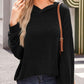 Woman wearing black textured kangaroo pocket long sleeve hoodie with slightly stretchy material and a casual outfit outdoors.