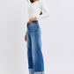 Stylish model in white top showcasing Judy Blue Full Size Distressed High Waist Wide Leg Jeans with chic cuffed hems.