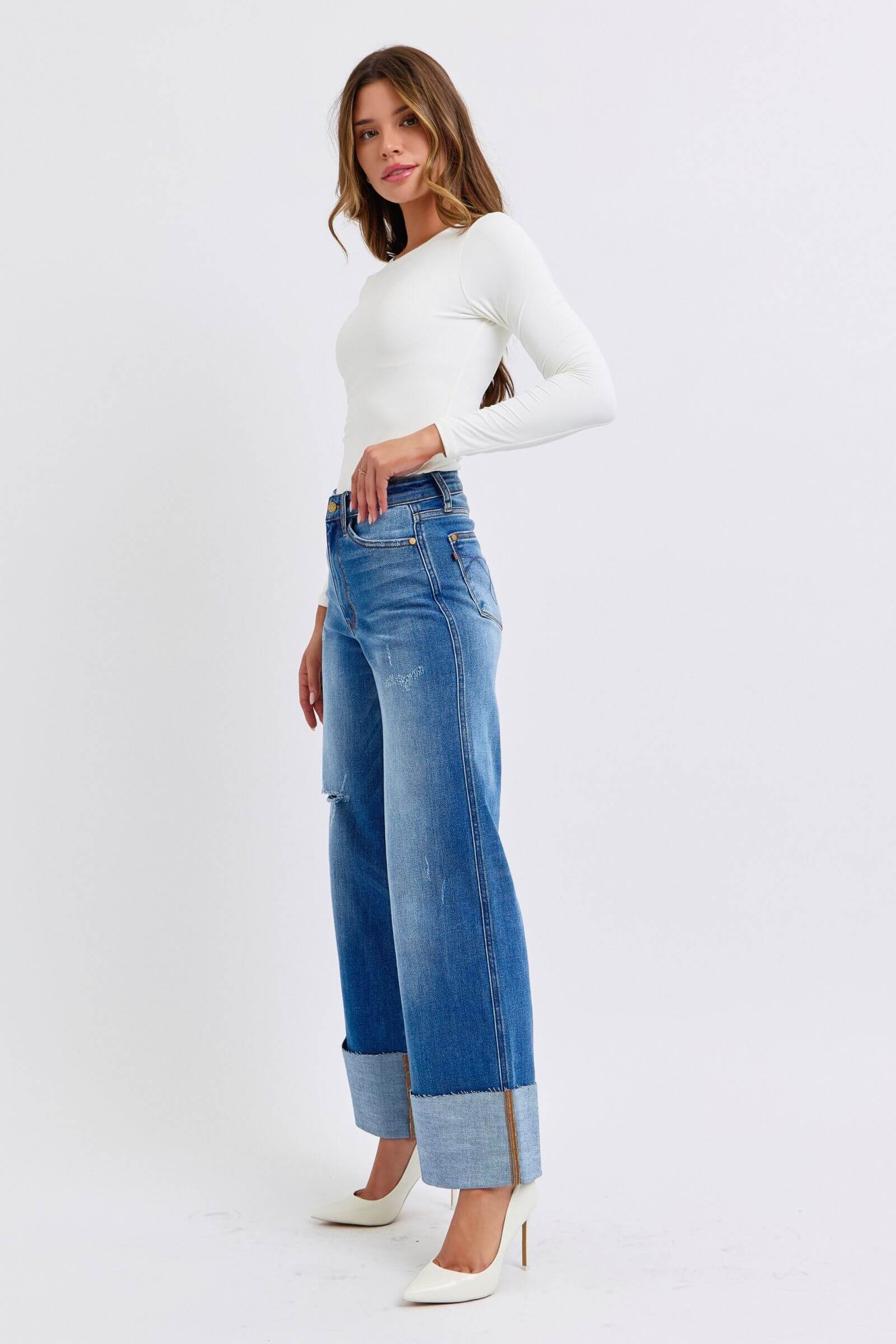 Stylish model in white top showcasing Judy Blue Full Size Distressed High Waist Wide Leg Jeans with chic cuffed hems.