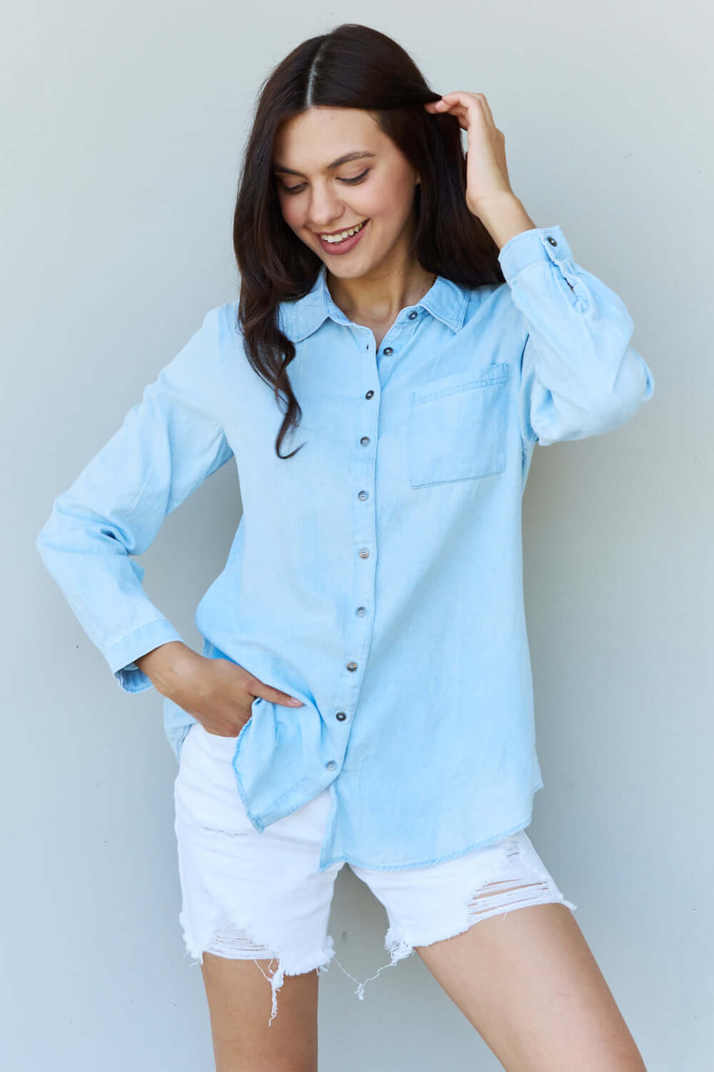 Woman wearing Blue Jean Baby Denim Button Down Shirt Top in light blue, featuring a classic button-up design with a pointed collar and long sleeves