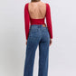 Woman in red backless top wearing Judy Blue raw hem mid-rise jeans, showcasing a trendy casual style.