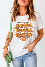 Woman wearing Bella Road THANKFUL Round Neck Short Sleeve T-Shirt in white with "thankful" graphic, holding a green purse.