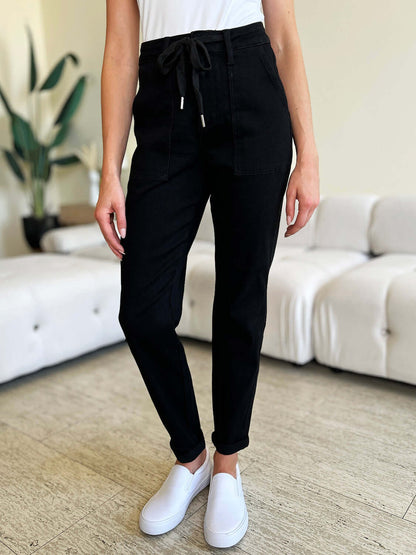 Woman wearing High Waist Double Roll Cuff Jeans by Judy Blue Jeans standing in stylish living room.