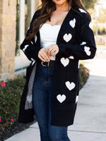 Woman wearing Bella Road Heart Open Front Long Sleeve Cardigan with white heart patterns, paired with a white top and jeans.