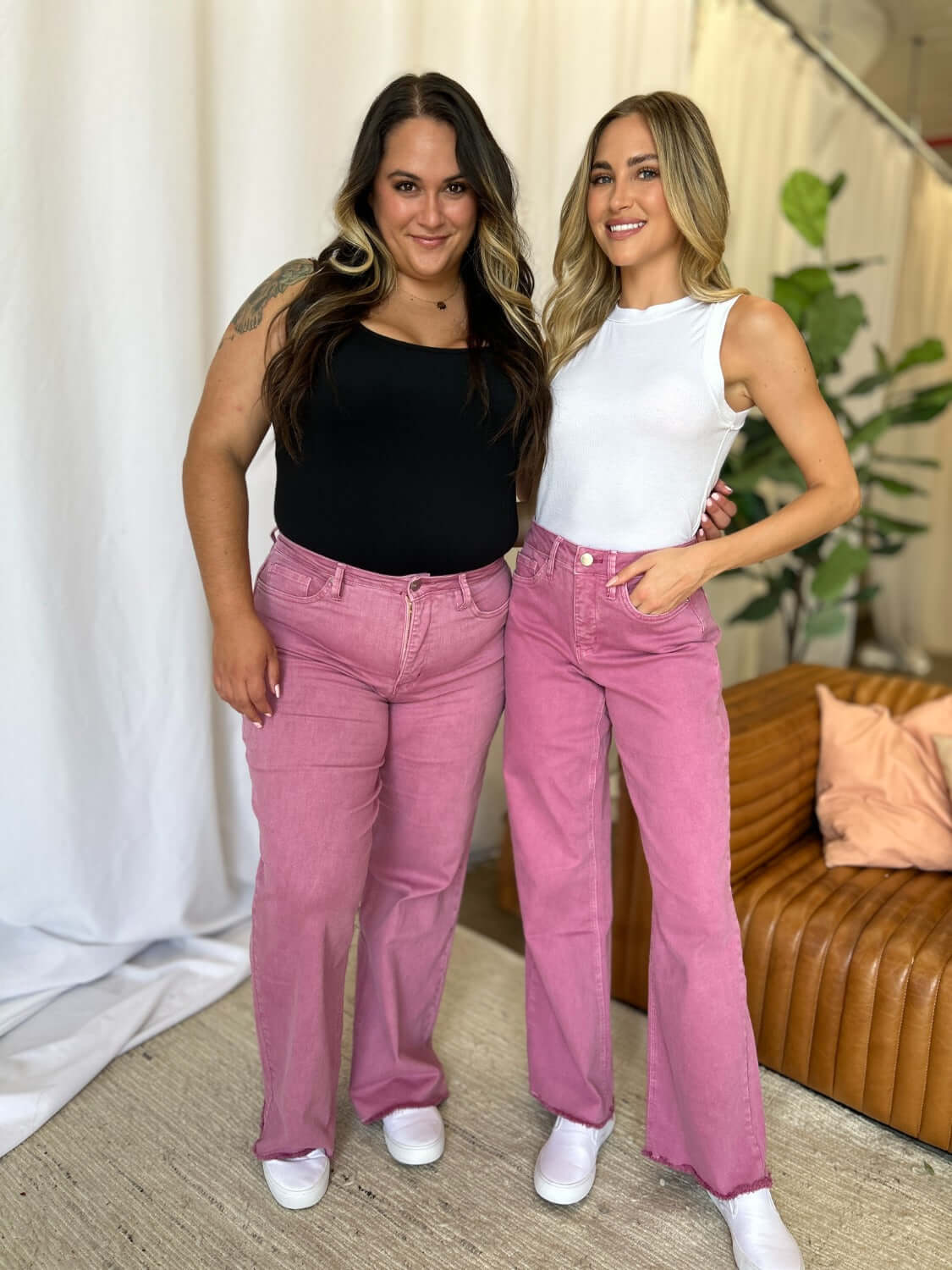 Two women wear stylish pink RFM Full Size High Rise Garment Dye Wide Leg Jeans, showcasing a relaxed, chic look with a soft, lived-in feel.