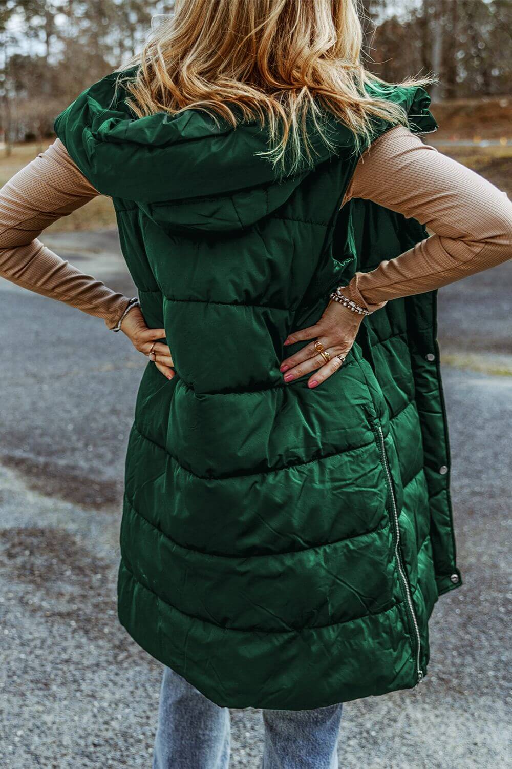 Woman wearing green Bella Road Longline Hooded Sleeveless Puffer Vest, showing back view and versatile layering style.