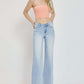 Woman wearing RISEN Wide Leg V Dipped Front Waist Jeans in light denim, paired with a peach tube top, showcasing a modern, stylish look