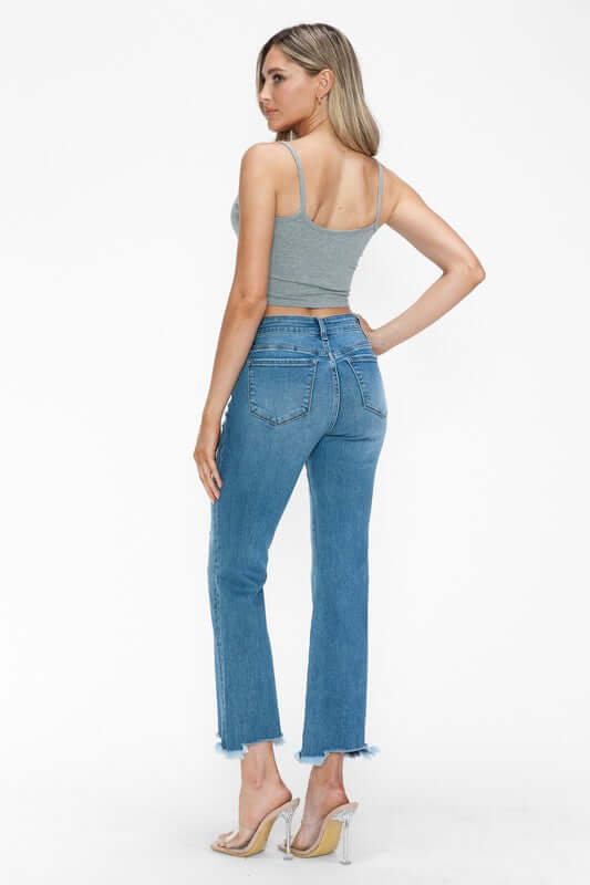 Model showcasing bytos Raw Hem Distressed Mid Rise Crop Jeans from the back, highlighting the stylish raw hem and fitted design.