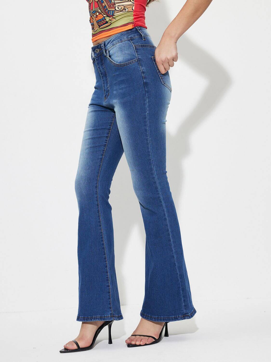 Woman wearing mid-rise waist bootcut jeans with pockets, button closure, and no stretch. Made of 85% cotton and 15% polyester.