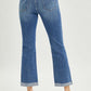 Back view of Button Fly Cropped Bootcut Jeans by Risen Jeans with frayed hems, styled with black heels.