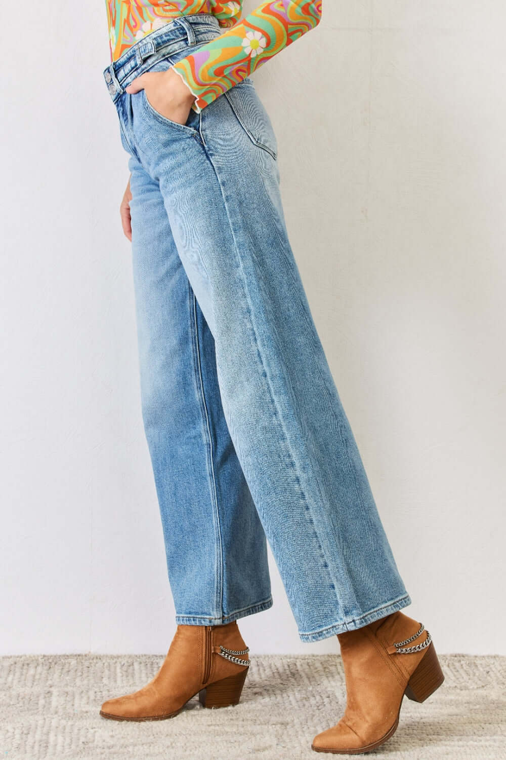 High Waist Wide Leg Jeans with slant pockets, zipper fly, and front pleats paired with brown ankle boots and a colorful top.