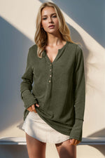 Woman wearing Double Take full size notched thumbhole long sleeve t-shirt in olive green with buttoned neckline and white skirt.