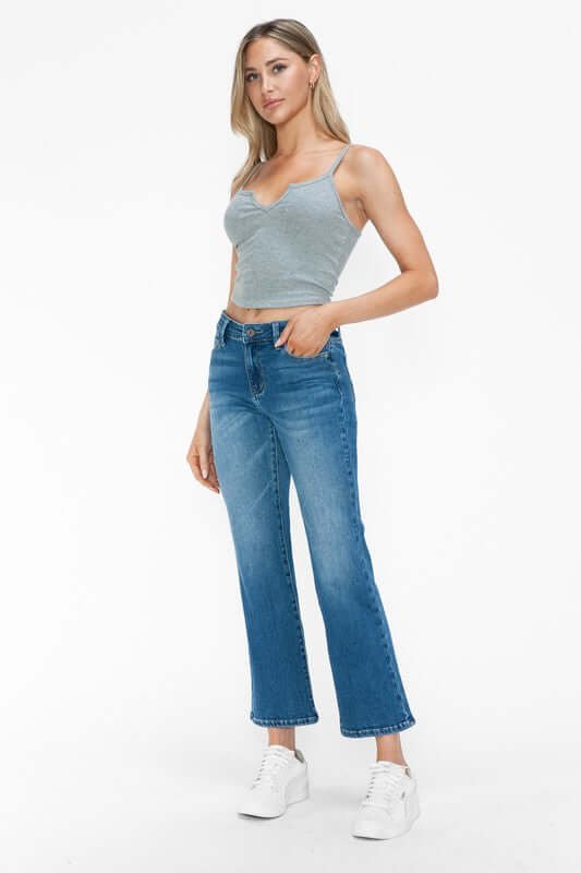 Stylish model wearing bytos Cat's Whiskers Mid Rise Ankle Jeans with a grey crop top and white sneakers.