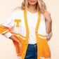 Woman wearing Haptics V Neck Button Down Letter Patch Cardigan with long sleeves and oversized fit in white and orange for a cozy, trendy look