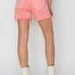 Back view of Risen Jeans High Rise Distressed Denim Shorts in pink, paired with white boots, showcasing trendy frayed hems.