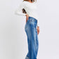 Model showcasing Judy Blue distressed high waist wide leg jeans in a side pose, highlighting stylish denim and relaxed fit.