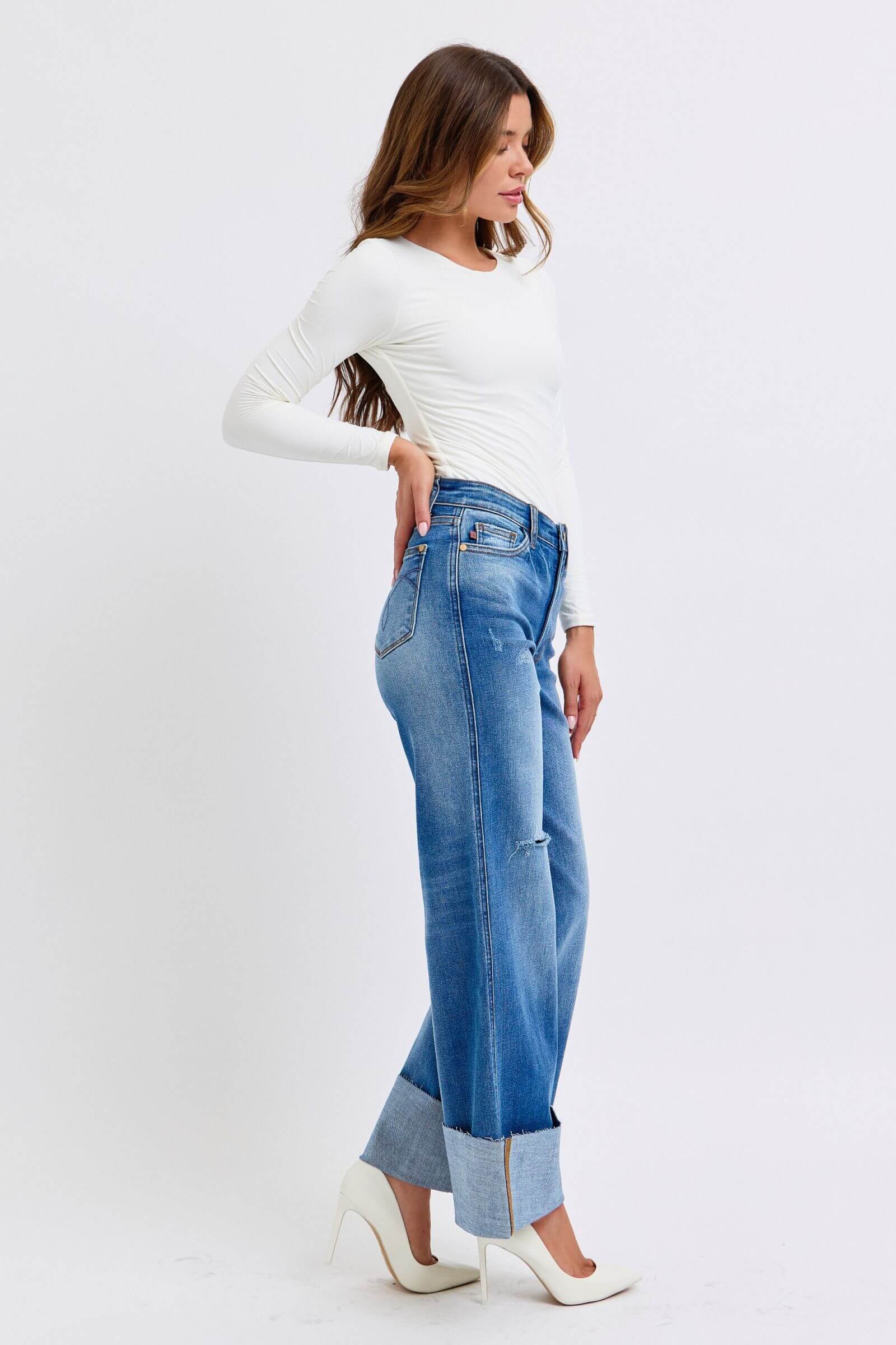 Model showcasing Judy Blue distressed high waist wide leg jeans in a side pose, highlighting stylish denim and relaxed fit.