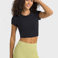 Young woman in black cropped sports t-shirt and green leggings, perfect for yoga or fitness activities.