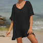 Woman wearing a black tied ruffled half sleeve cover-up at the beach, made of sheer fabric, 65% cotton, 35% polyester, machine washable.