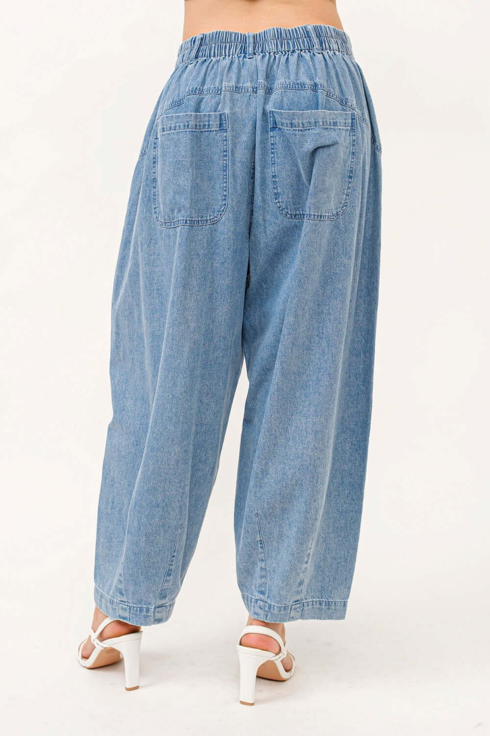 Back view of elastic waistband pleated baggy jeans in light denim, featuring pocket details and relaxed fit.