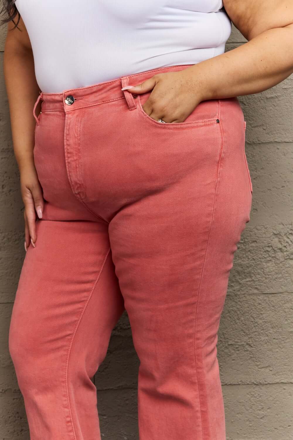 Woman wearing Bailey High Waist Side Slit Flare Jeans in coral pink, crafted from stretchy denim and designed to accentuate curves.