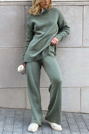 Stylish woman in green turtleneck side slit sweater and matching pants, holding coffee cup, showcasing cozy, relaxed fashion style.