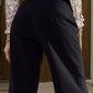 Woman wearing black wide leg jeans with pockets, back view.