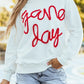 Woman wearing Bella Road Game Day Round Neck Long Sleeve Sweatshirt with "game day" text and denim shorts.