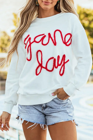 Woman wearing Bella Road Game Day Round Neck Long Sleeve Sweatshirt with "game day" text and denim shorts.