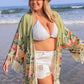 Plus size woman in a floral fringe cover-up at the beach, showcasing a bikini and sunny vibes.