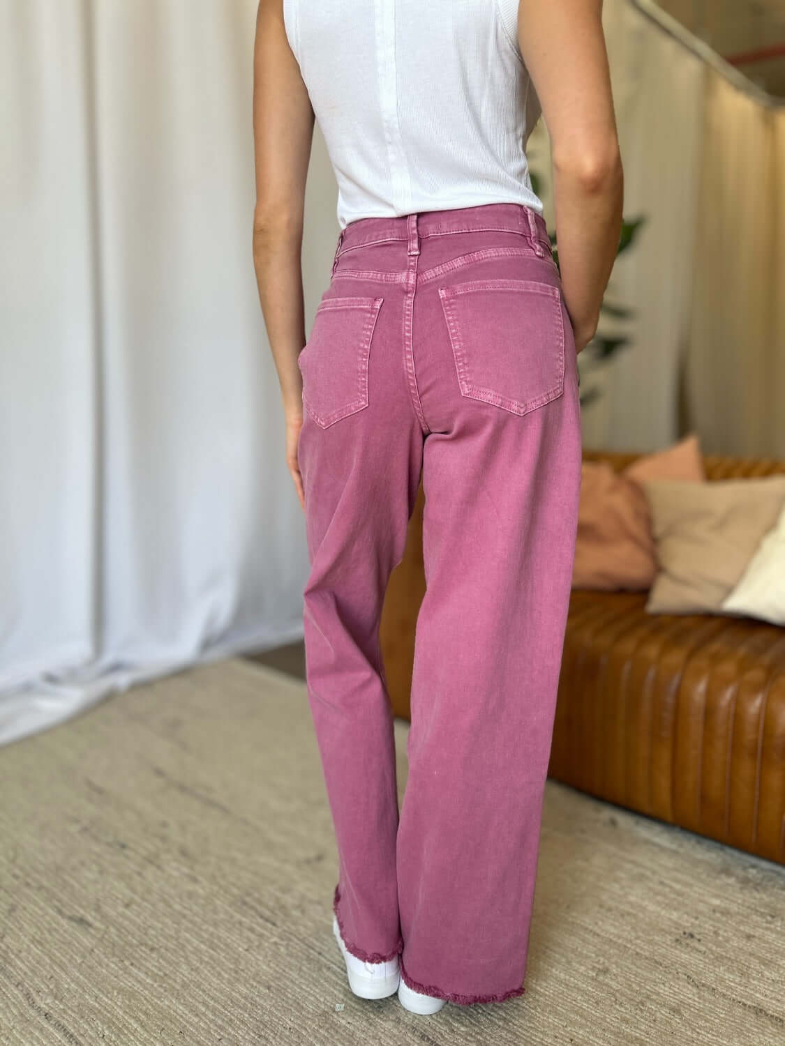 Woman wearing RFM Full Size High Rise Garment Dye Wide Leg Jeans in pink color, showcasing the stylish wide-leg silhouette.