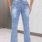 Woman wearing light blue bootcut jeans with back pockets, showcasing slim fit and high stretch material.