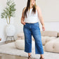 Woman wearing Judy Blue braid side detail wide leg jeans with a white top and black heels standing in a modern living room.