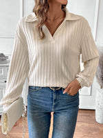 Woman wearing ribbed Johnny collar long sleeve t-shirt in white paired with blue jeans and holding a white clutch.