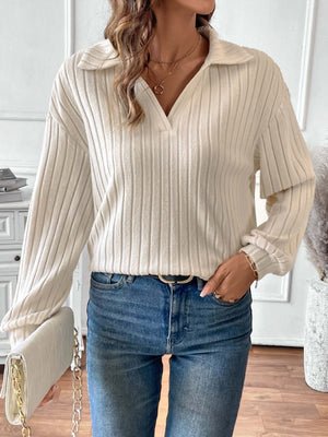 Woman wearing ribbed Johnny collar long sleeve t-shirt in white paired with blue jeans and holding a white clutch.