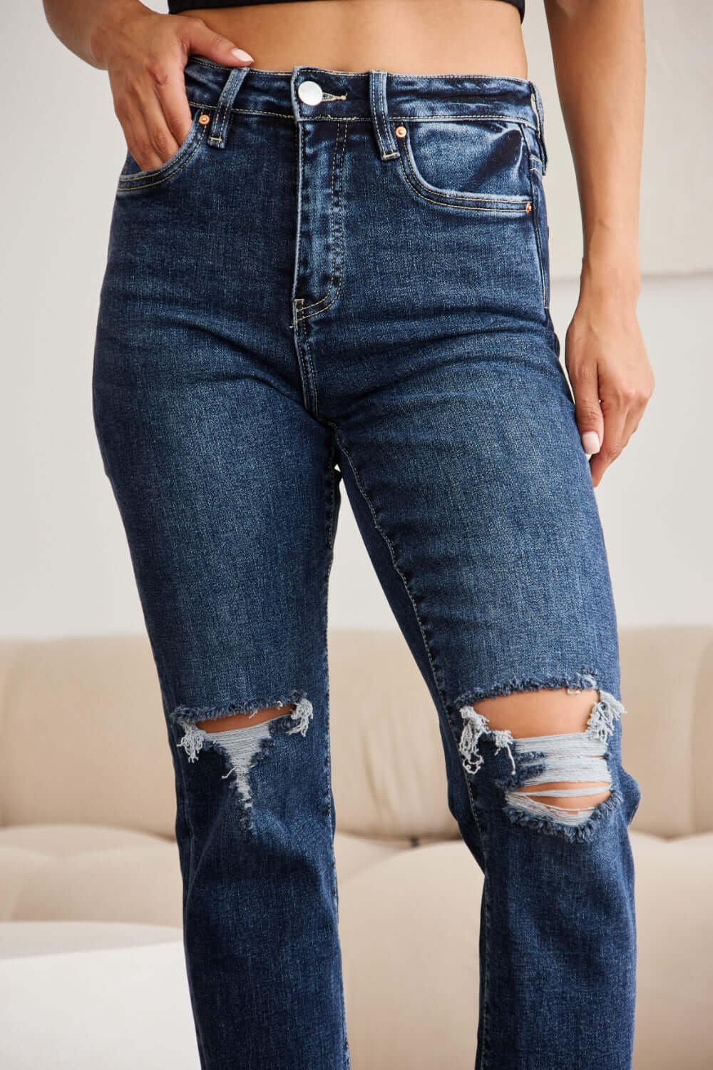 Woman wearing RFM Jeans Crop Dylan Full Size Tummy Control Distressed High Waist Raw Hem Jeans showcasing trendy distressed details.