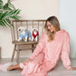 Cozy model in dusty pink hooded midi lounge dress, sitting with plush dogs on a chair, perfect for fall lounging.