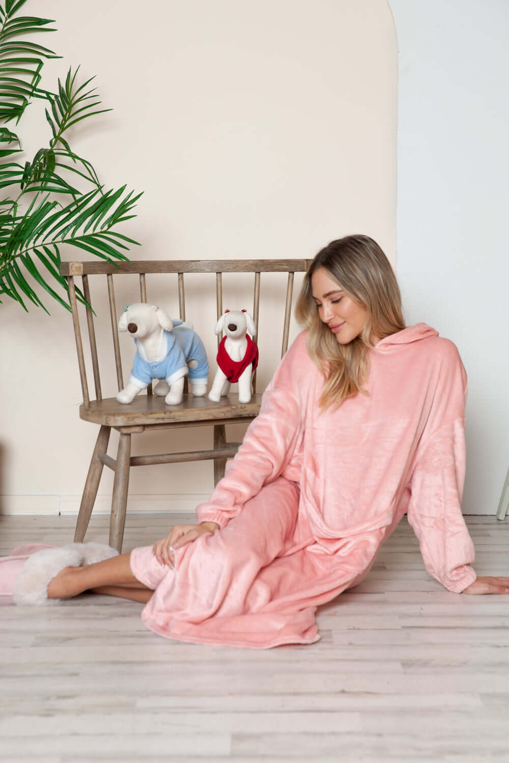 Cozy model in dusty pink hooded midi lounge dress, sitting with plush dogs on a chair, perfect for fall lounging.