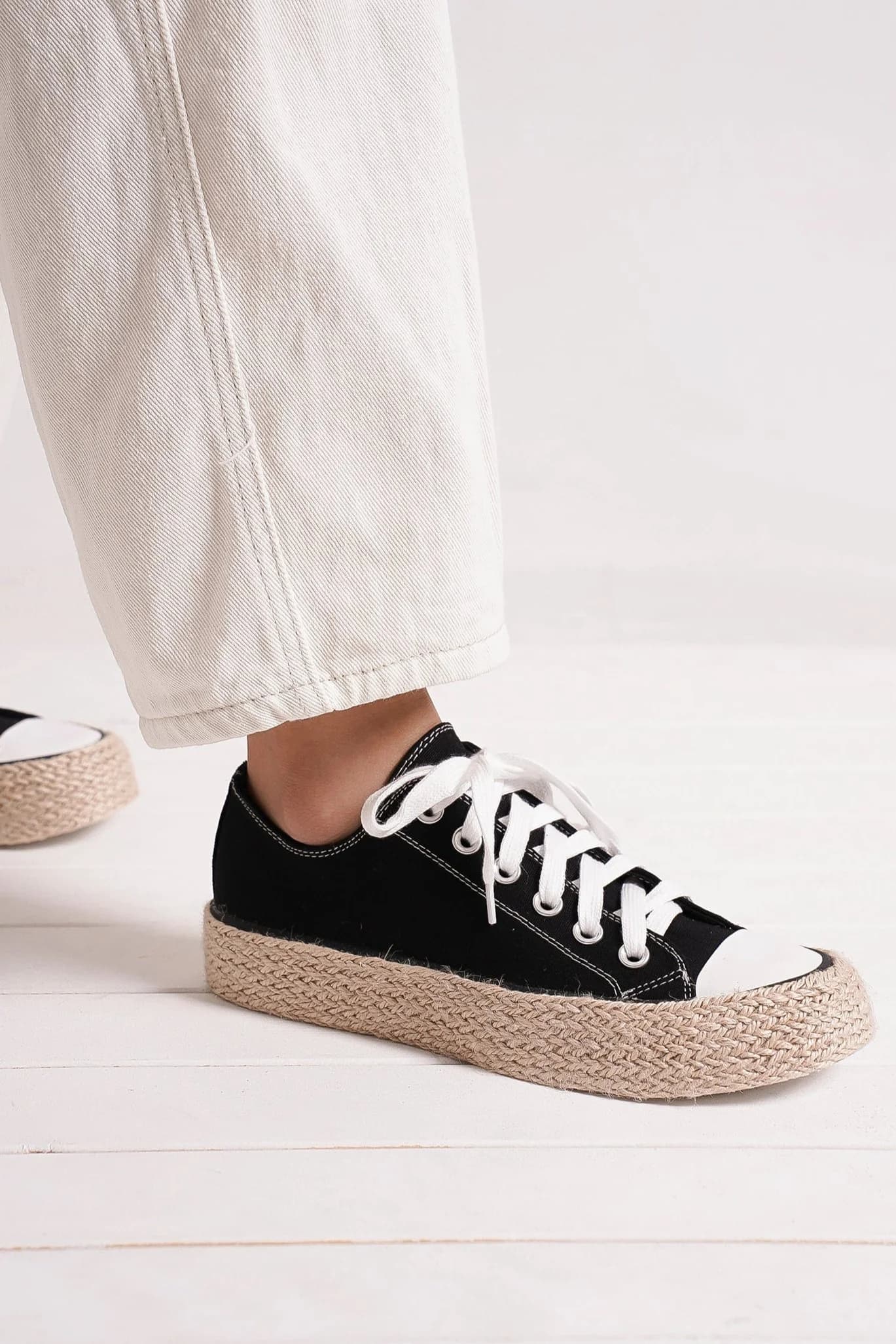 Black lace-up sneakers with woven espadrille sole, perfect for summer style and comfort.