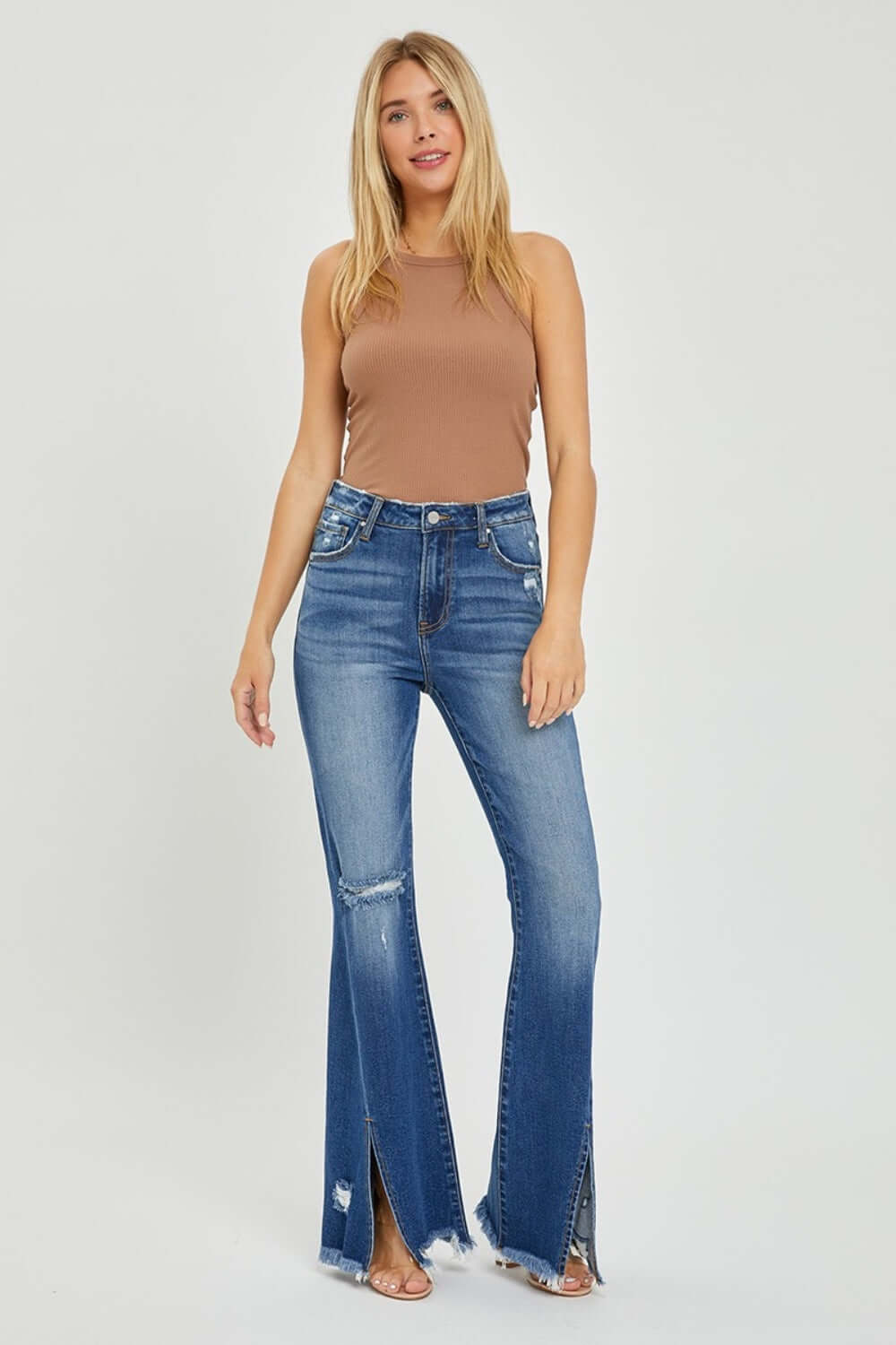 Woman wearing High Rise Front Slit Frayed Hem Flare Jeans by Risen, showcasing trendy high-rise design, front slit, frayed hem, and flared silhouette.