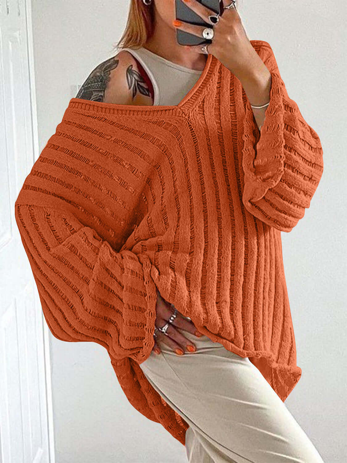 Woman wearing Bella Road orange V-neck long sleeve sweater with cozy distressed design, perfect for trendy fall outfits.