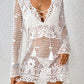 Woman wearing a white cutout tied V-neck long sleeve crochet cover-up with floral details.